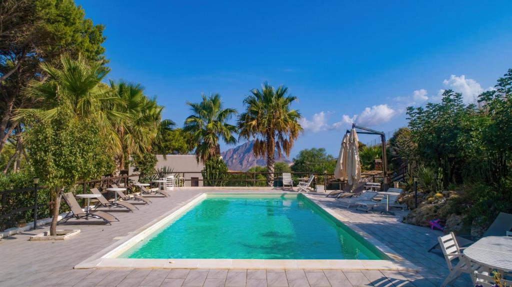 a swimming pool with palm trees and chairs at Villa Panoramica sul Mare in Valderice