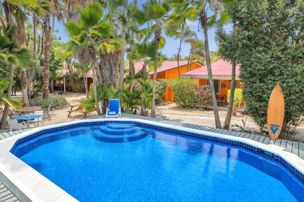 a swimming pool in front of a house with palm trees at Tropical Divers Resort in Kralendijk