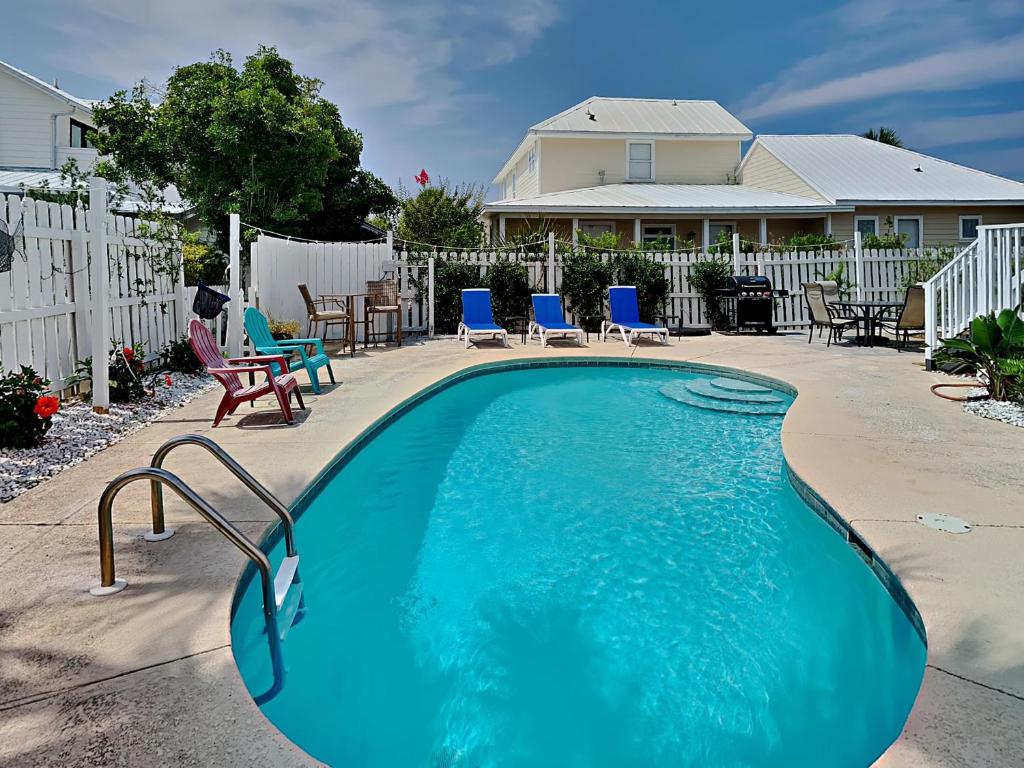 une piscine avec des chaises bleues et une maison dans l'établissement Reality Break, à Destin