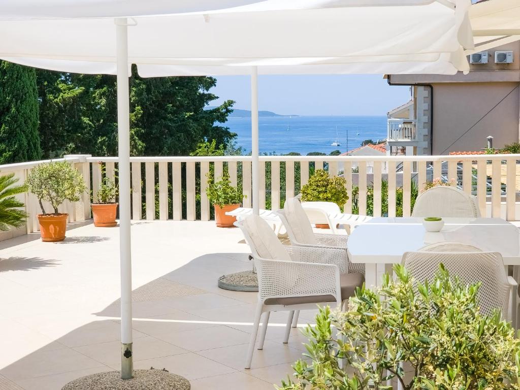 a white umbrella on a patio with a table and chairs at Apartments Nikolina in Hvar