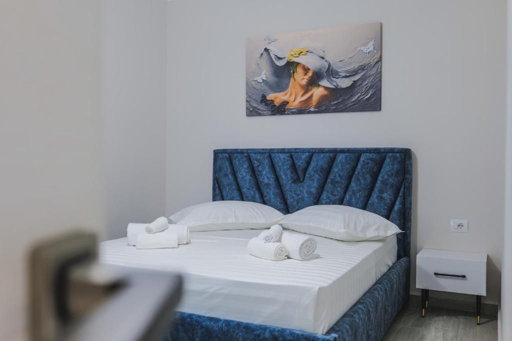 a bedroom with a bed with a painting on the wall at Luka Apartments in Sarandë