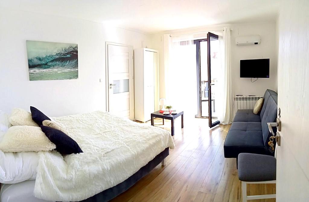 a white bedroom with a bed and a couch at Ludna 3 in Niechorze
