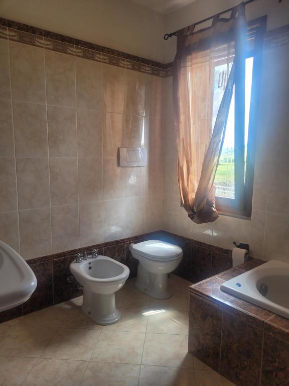bagno con due servizi igienici, lavandino e finestra di Il risveglio a Codrongianos