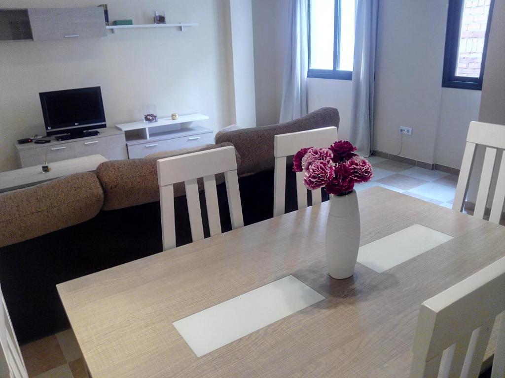 a living room with a table and a vase with flowers on it at Apartamentos Decada Malaga in Málaga