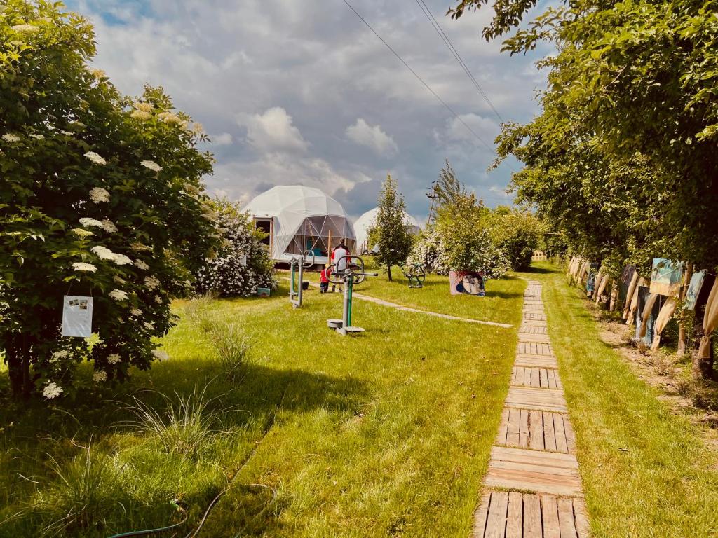 a garden with a greenhouse and a path in the grass at Glamping Stacja Zieleniec w Nałęczowie in Nałęczów