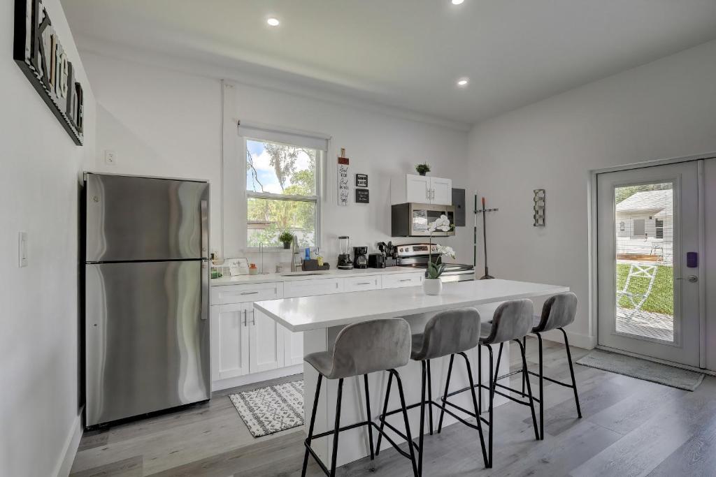a kitchen with a refrigerator and a table with stools at Guest House In a Downtown Bonita Springs Compound in Bonita Springs