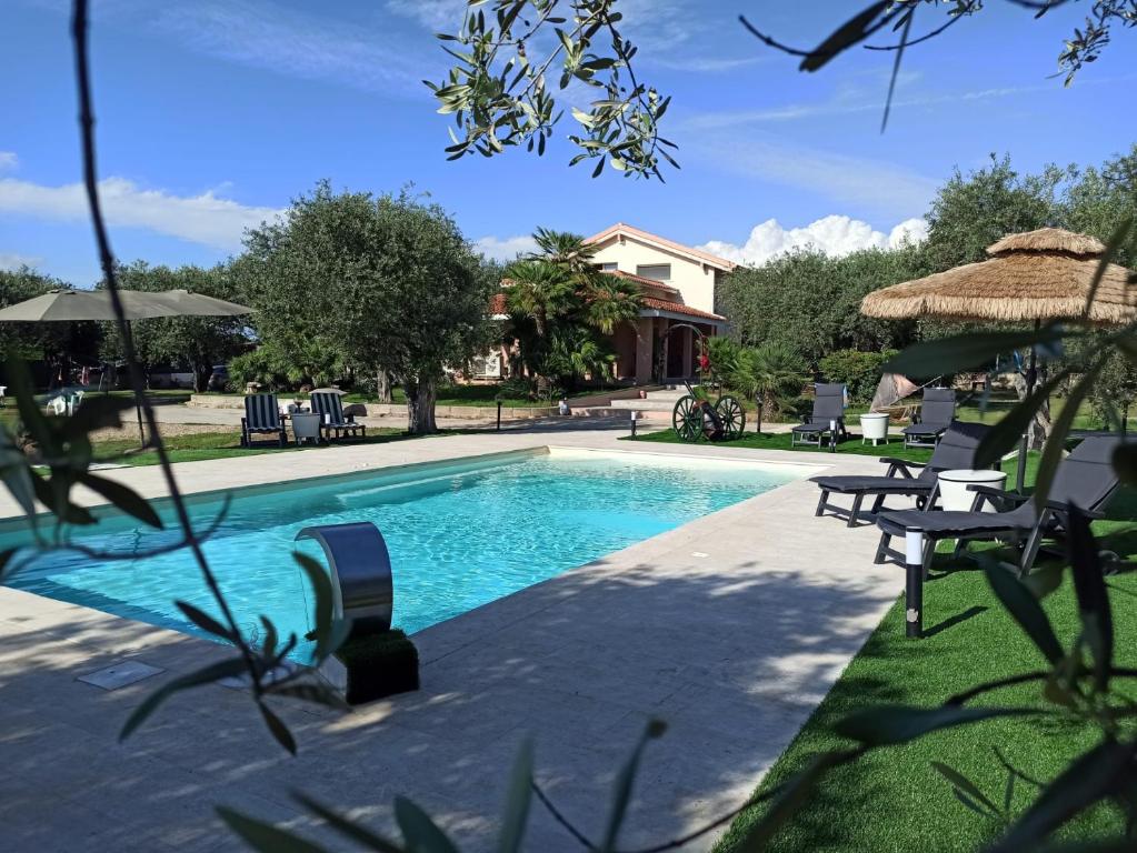 a swimming pool with chairs and umbrellas at Villa Marianna in Alghero