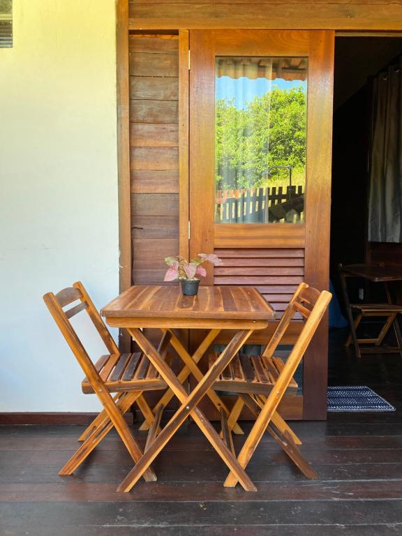 una mesa de madera y 2 sillas en el porche en Chalés Paradise en Atins