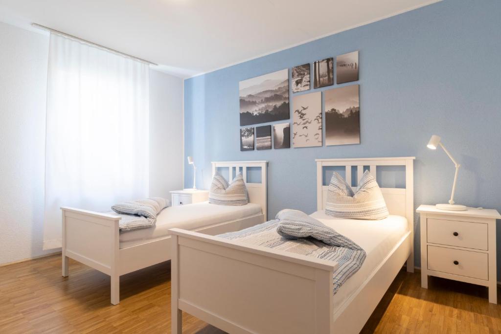 two beds in a room with blue walls at Haus Oselbach- Gemütlich, Zentral, Modern in Zweibrücken