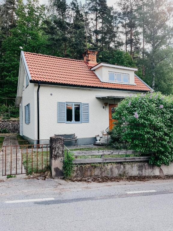 una pequeña casa blanca con techo naranja en Charming house with wood stove near lake, en Virserum