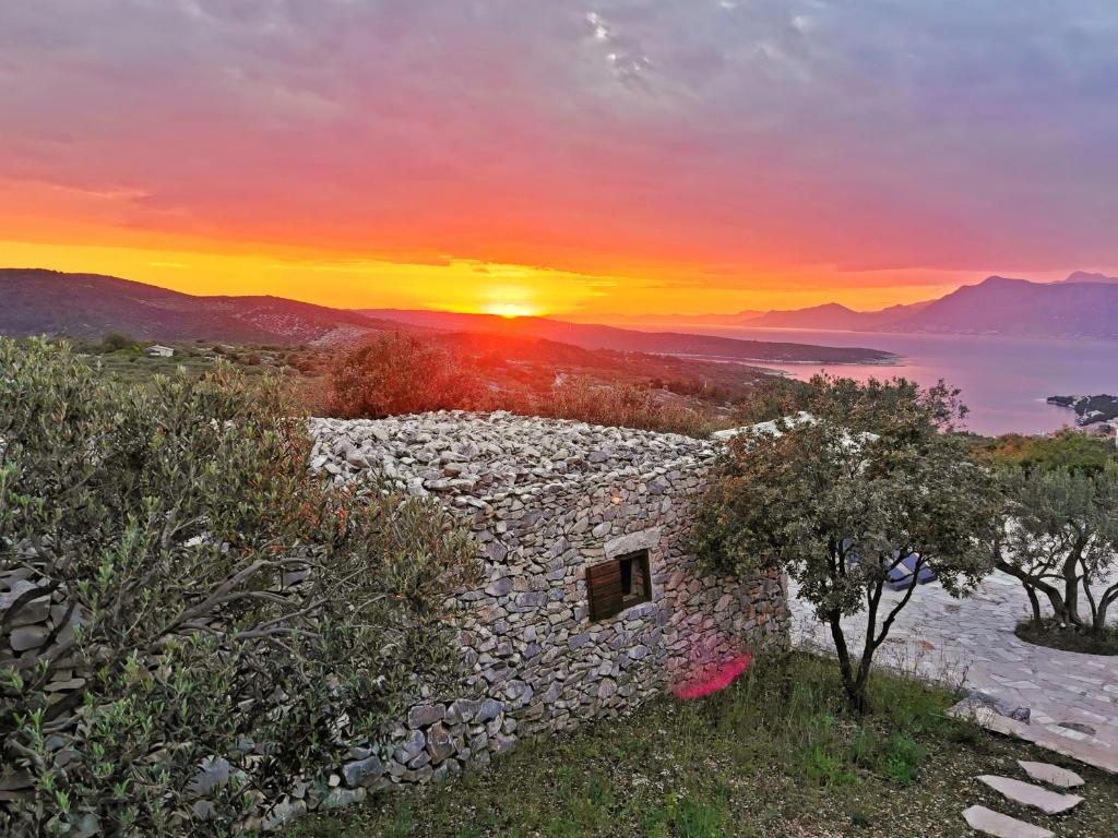 a sunset over the ocean with a stone building at Villa Viva Brac - Pool - Meerblick in Povlja