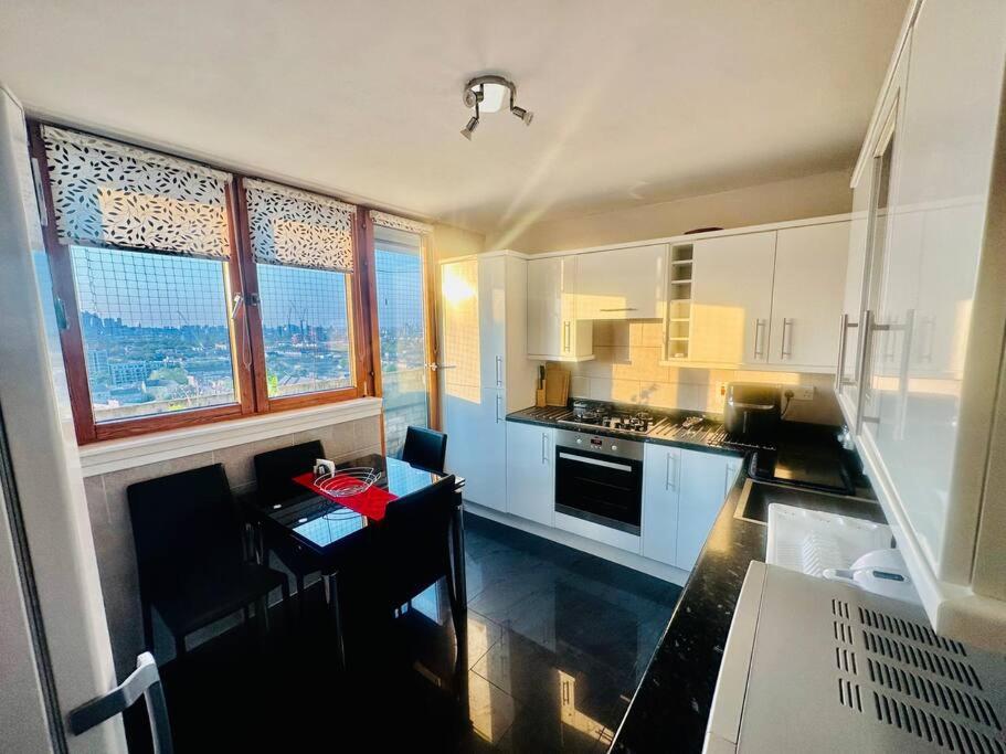 a kitchen with white cabinets and a small table in it at 3 bed Sky apartment SE15 Peckham in London