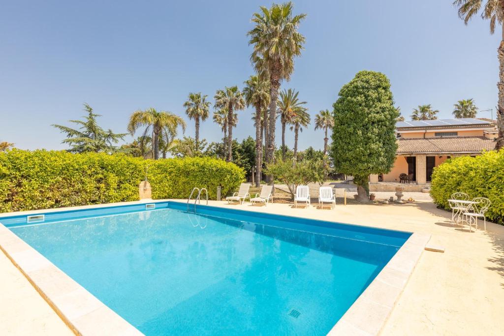una piscina con palmeras y una casa en Villa dell'edera en Melissano