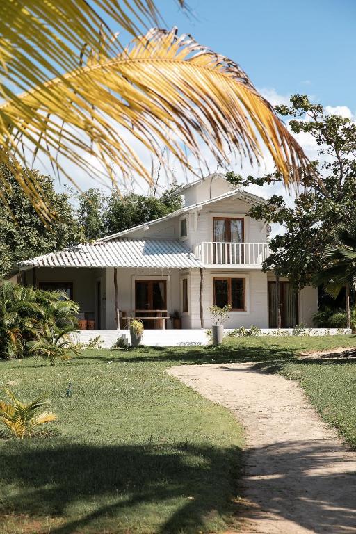 a white house with a palm tree in front of it at KANAHA BEACH VILLA in Icaraí
