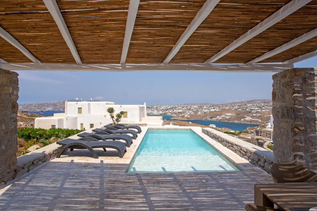 a swimming pool with chairs and a view of a city at Nuera Villa in Mýkonos City