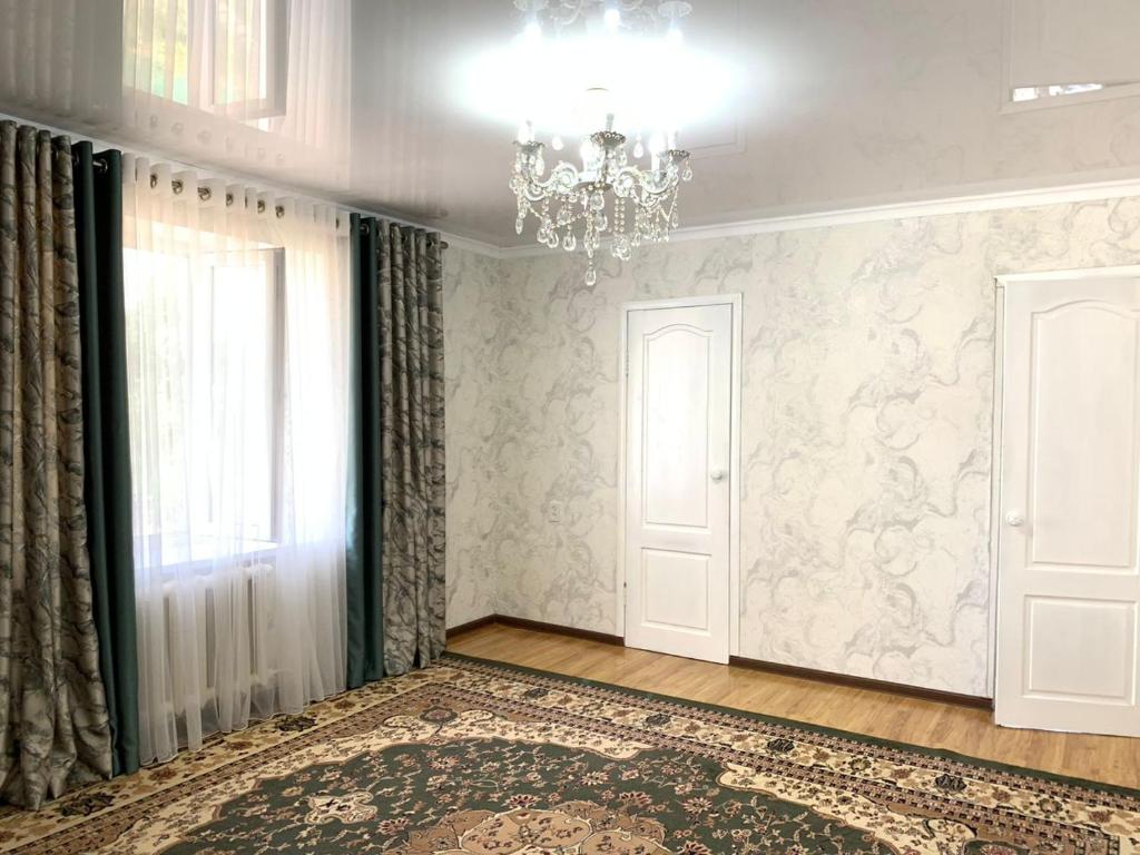 a room with a chandelier and a large rug at Guest House ak orgo in Bishkek