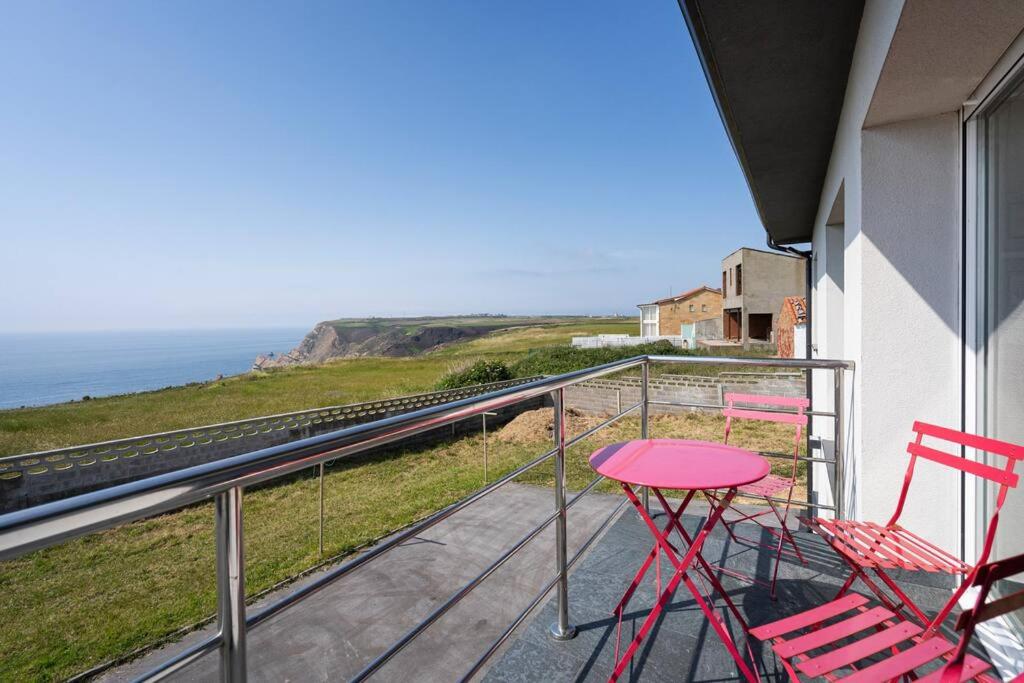 un balcón con sillas rojas, una mesa y el océano en MyHouseSpain - La Atalaya, casa frente al mar, 