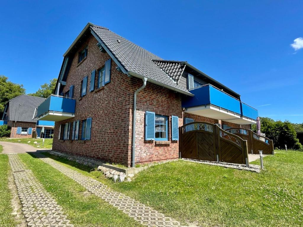a brick house with blue windows and a fence at Ferienwohnung 11 am Selliner See in Ostseebad Sellin