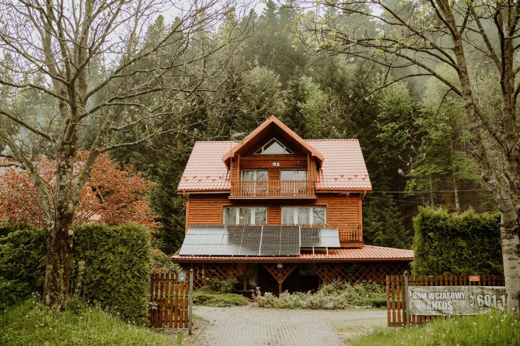 een houten huis met een balkon in het bos bij Pensjonat Antoś in Baligród