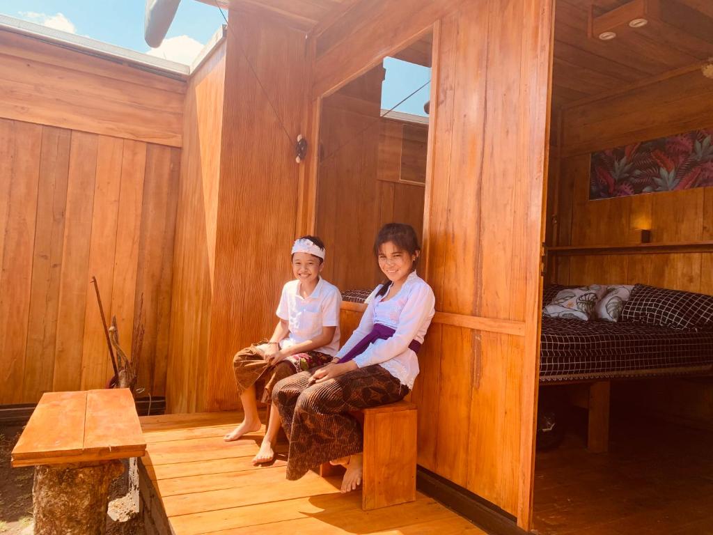 dwie kobiety siedzące w pokoju z łóżkiem w obiekcie Buahan Sweet Glamping ( BSG) w mieście Kubupenlokan