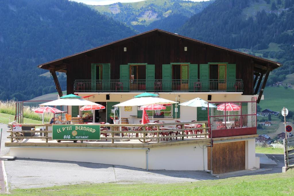a restaurant with tables and umbrellas in front of a building at Hôtel Les Bernards in Praz-sur-Arly