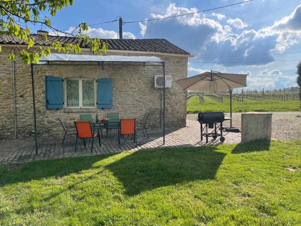 patio ze stołem, krzesłami i parasolem w obiekcie Le P'tit Gîte w mieście Pellegrue