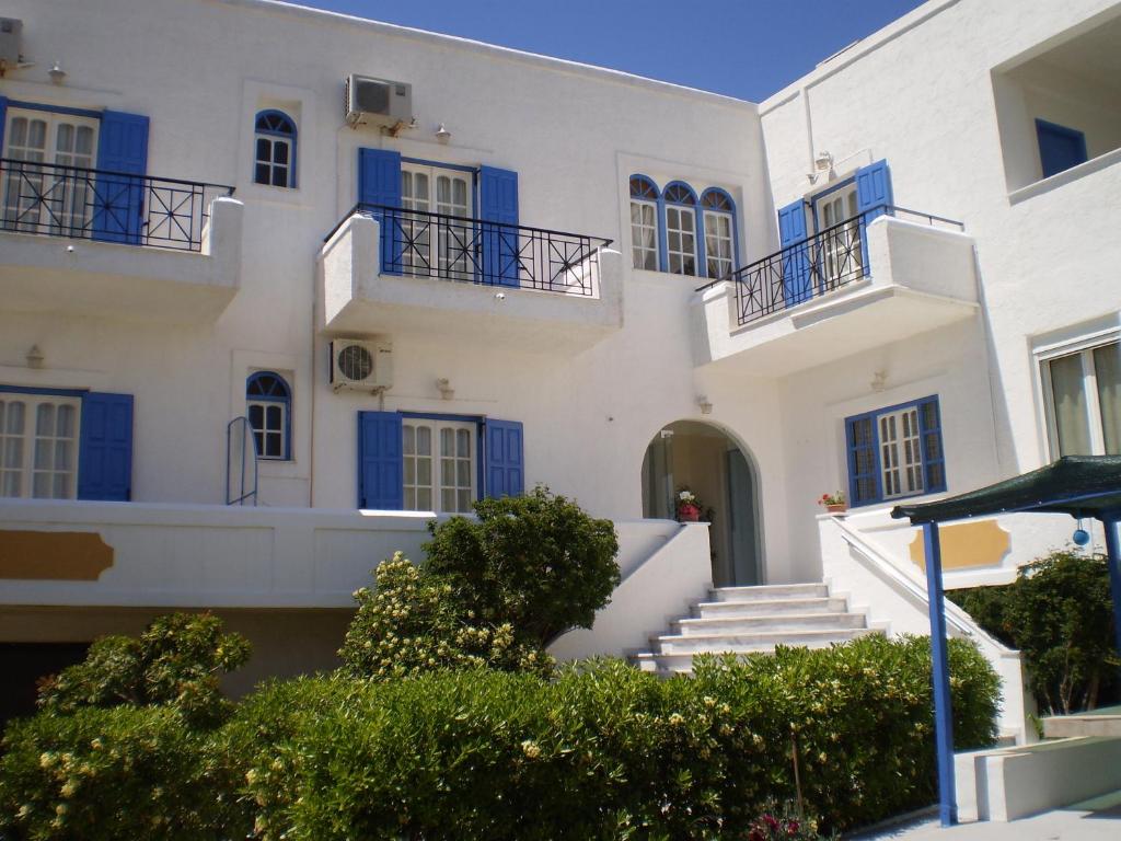 un gran edificio blanco con puertas y escaleras azules en Barbara II, en Agia Marina Aegina