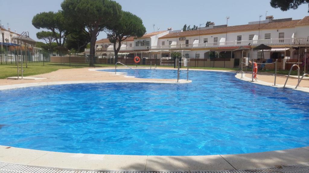 a large blue swimming pool in front of a building at Miramar in Mazagón