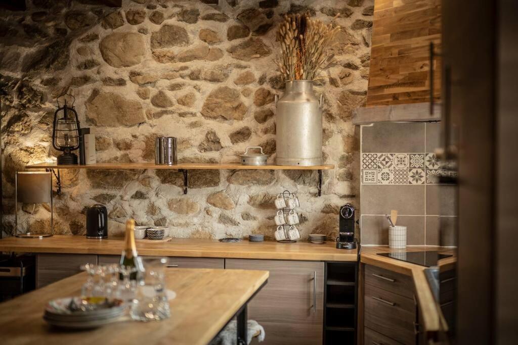 cocina con pared de piedra y mesa de madera en Venez Chez Vous - La Grange du Lac - Vue montagne en Saint-Jorioz