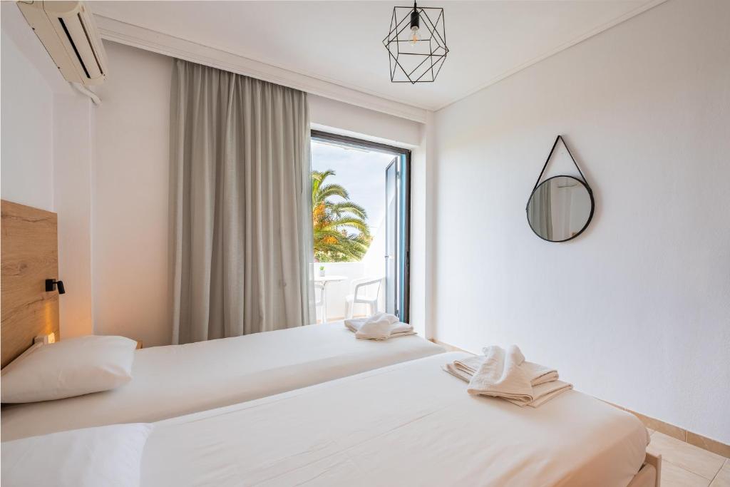 two beds in a white room with a window at Anthia Apartments in Marmari