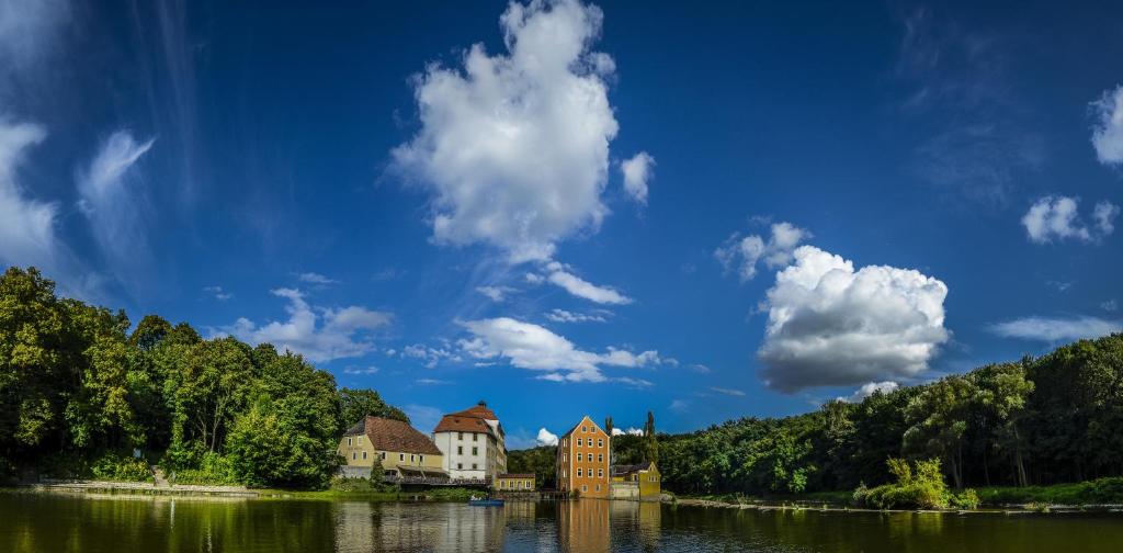 eine Gruppe von Gebäuden am Ufer eines Sees in der Unterkunft Hotel Obermühle in Görlitz