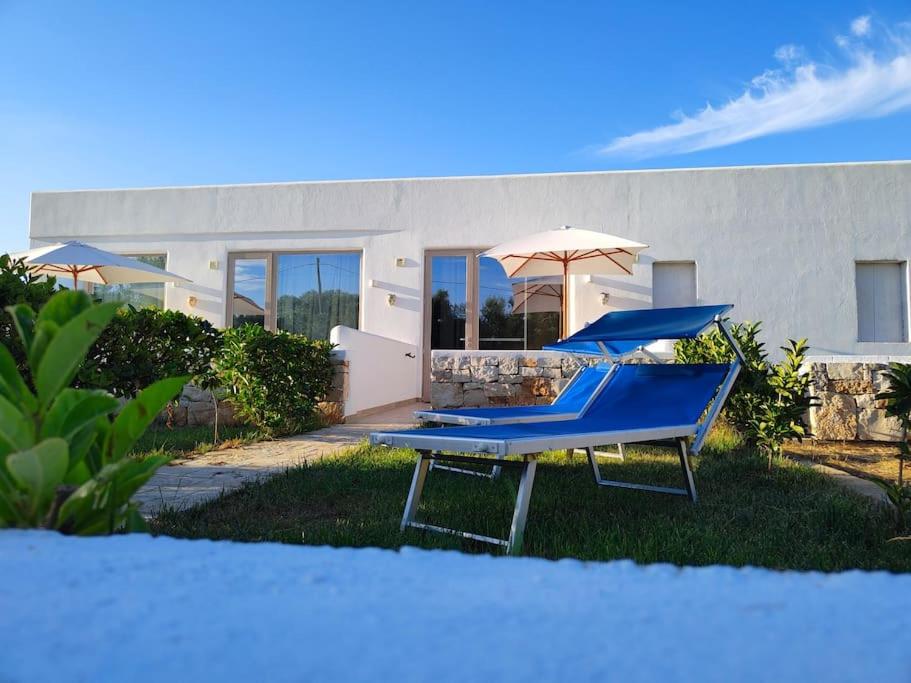- deux chaises bleues et un parasol devant une maison dans l'établissement Emanuela Apartments 1.0, à Torre Santa Sabina
