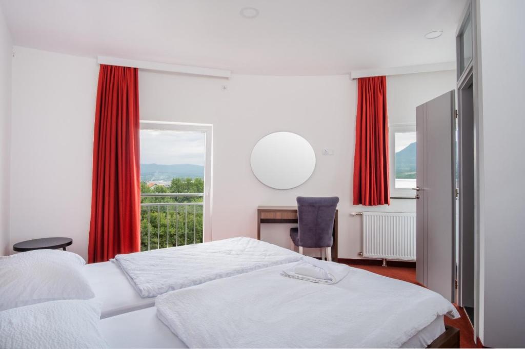 a bedroom with a bed and a window with red curtains at Kašmir in Bugojno