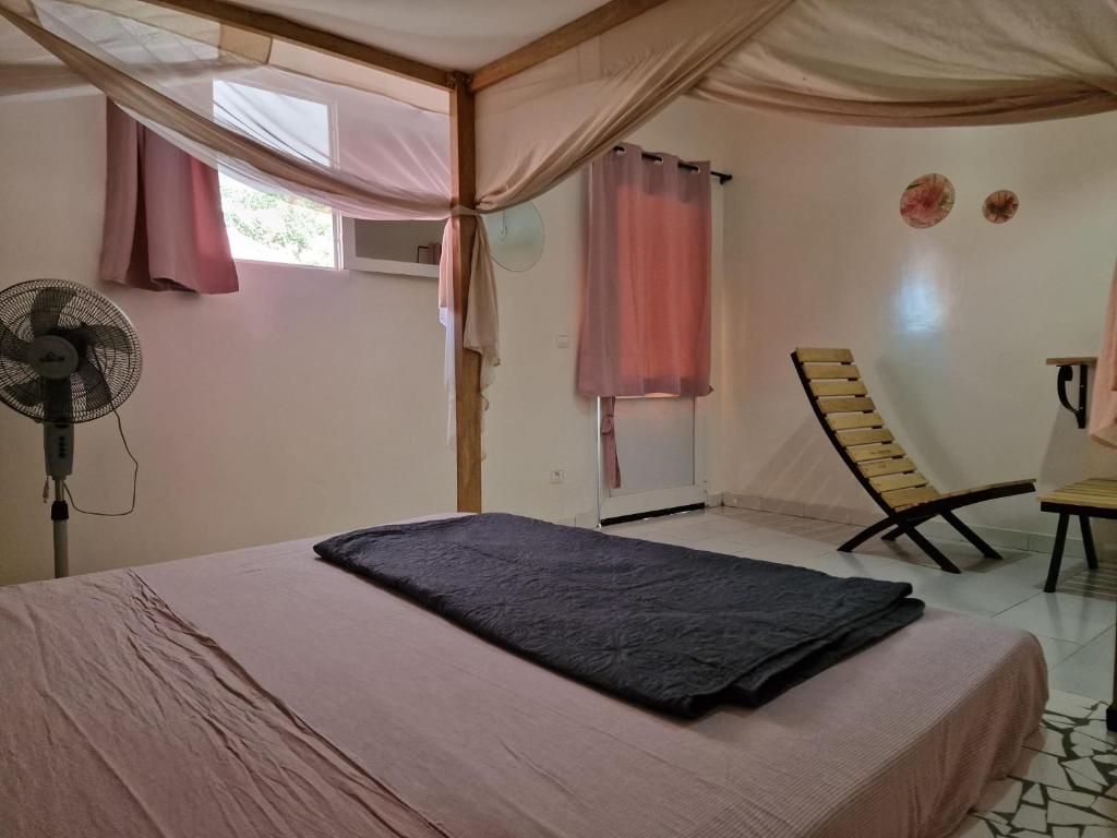 a bedroom with a bed and a fan and a window at Le Paradis in Nianing