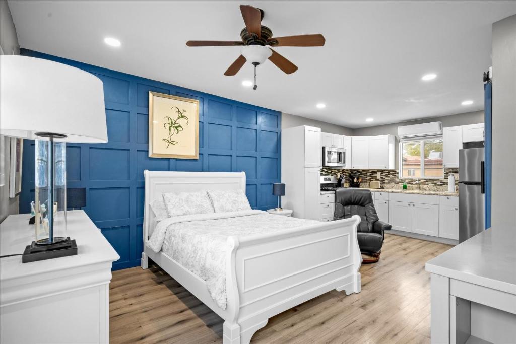 Chelsea Place في فينكس: غرفة نوم زرقاء مع سرير أبيض ومروحة سقف