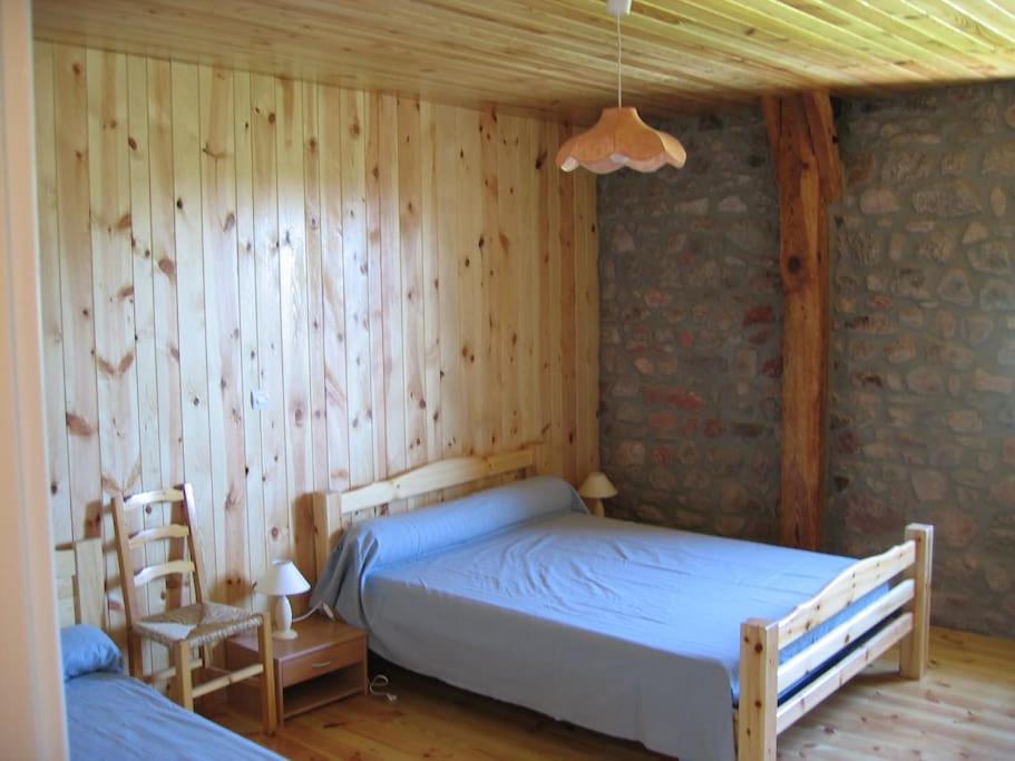 een slaapkamer met een bed en een houten muur bij Lozère St Alban Aubrac Margeride gîte 4 étoiles 8 personnes au calme près nature in Saint-Alban-sur-Limagnole