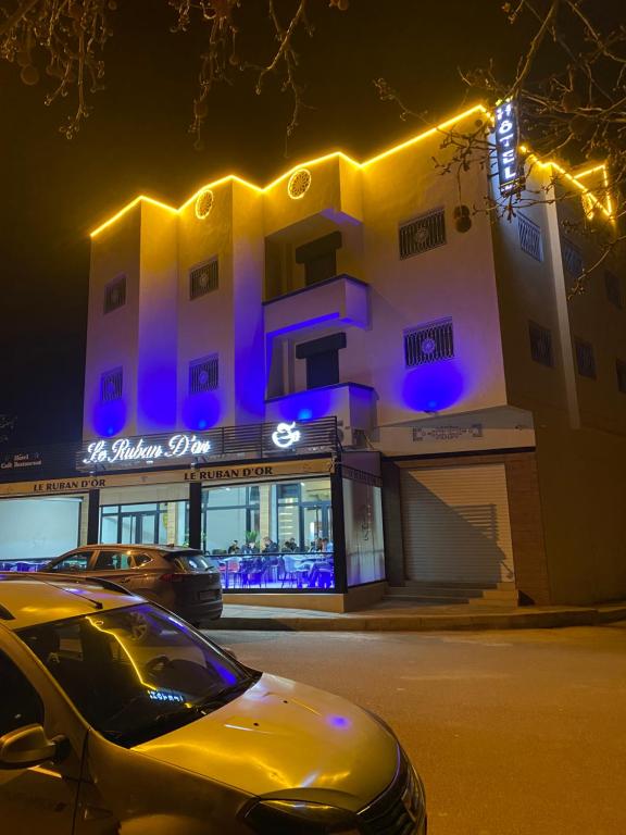 um carro amarelo estacionado em frente a um edifício à noite em Le ruban d’or em Azilal