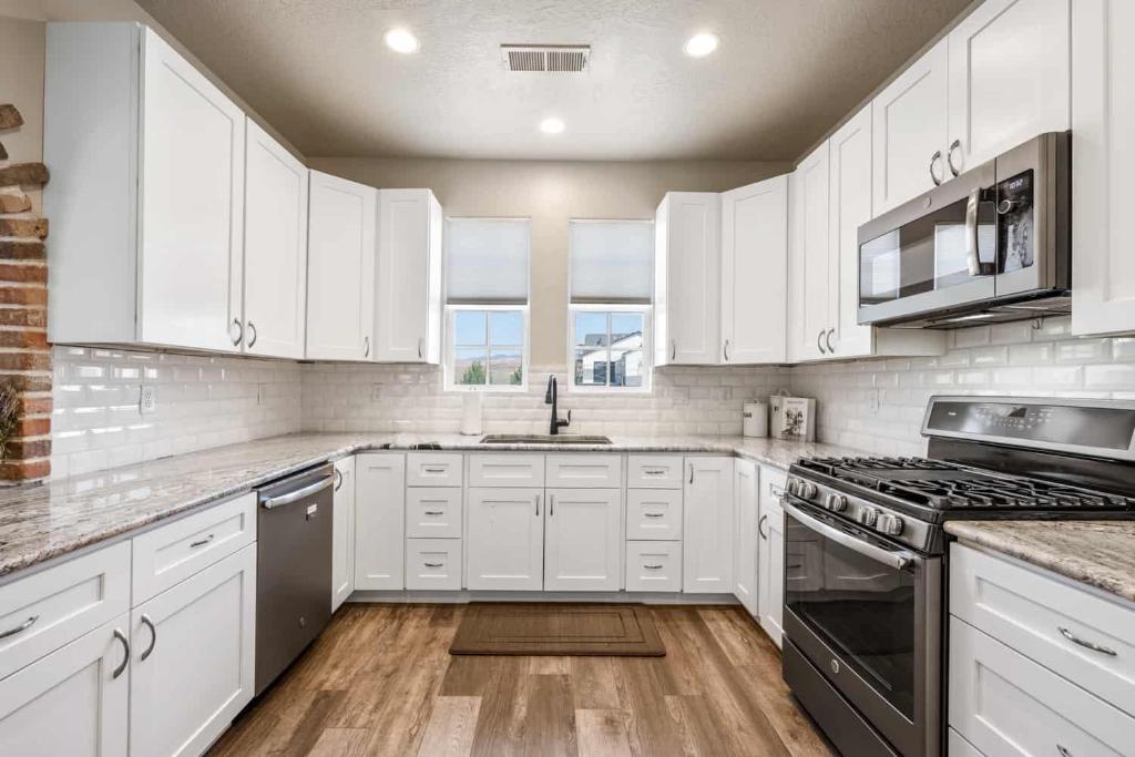 a kitchen with white cabinets and a stove top oven at The Ella home in Hurricane