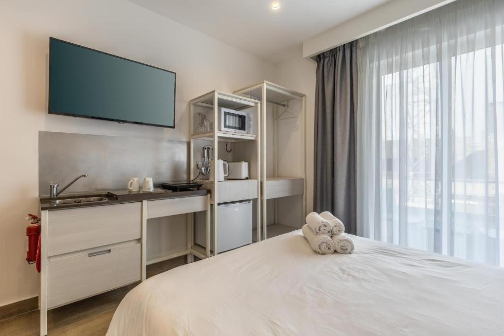 a bedroom with a bed with a tv on the wall at Private studio room 13 at OLO Living nestled in St Julians in Paceville