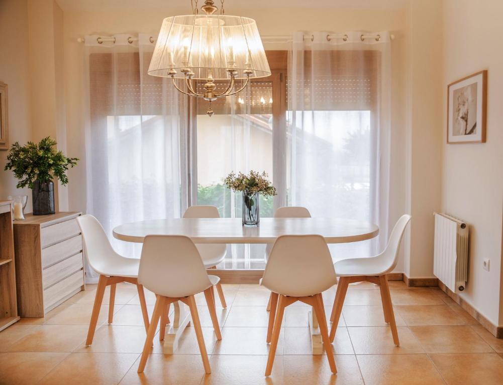 einen Esstisch mit weißen Stühlen und einem Kronleuchter in der Unterkunft Casa amplio jardín próximo al Parque Cabarceno in Penagos