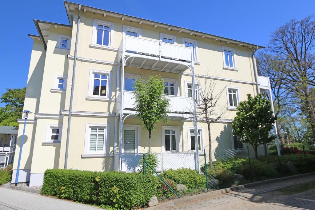 a large white house with bushes in front of it at Villa Strandmuschel Whg. 09 mit Balkon in Göhren