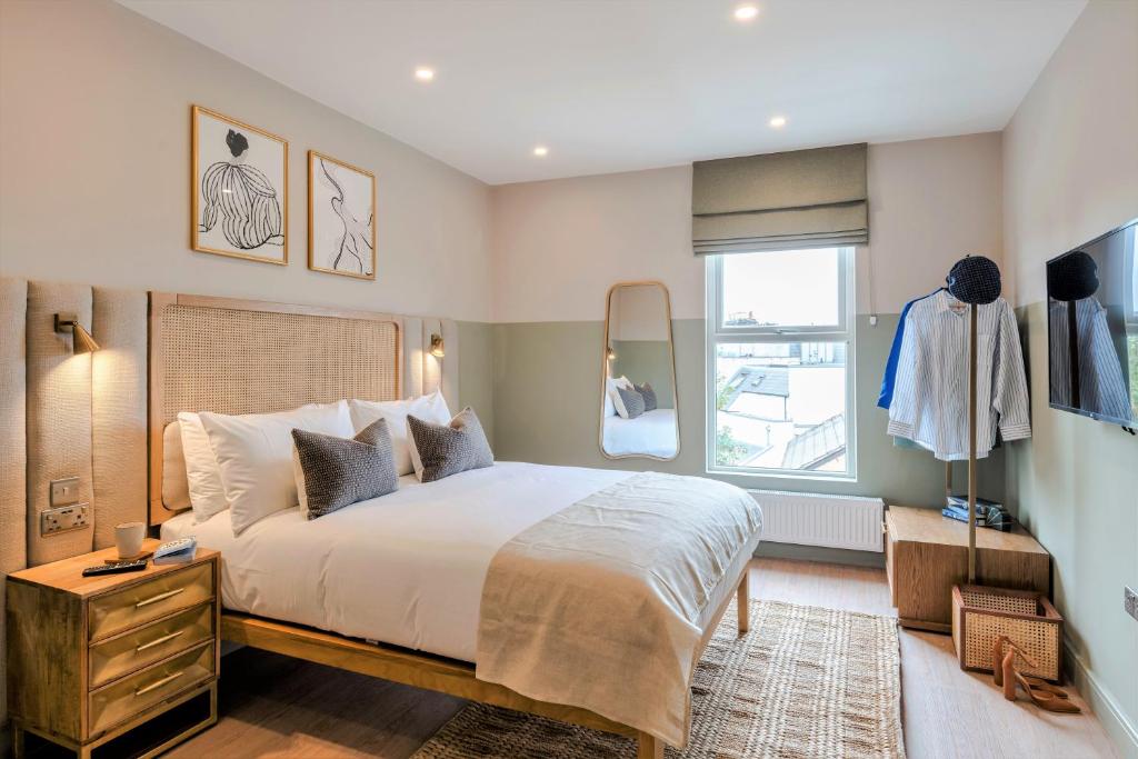 a bedroom with a large bed and a window at Shepherds Bush - Your Apartment in London