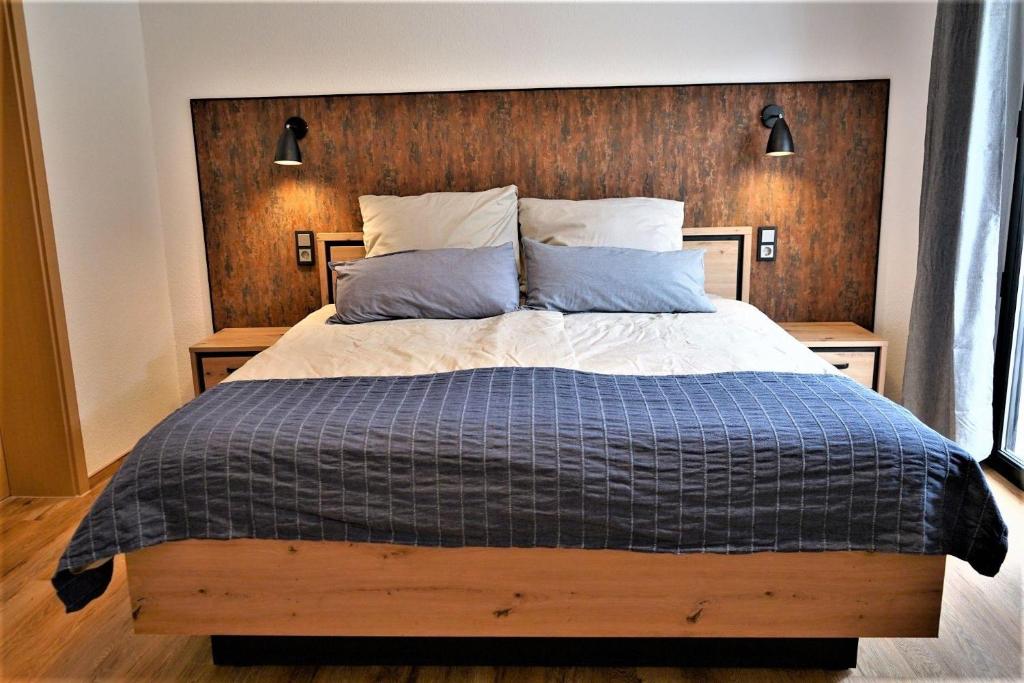 Un dormitorio con una cama grande con cabecero de madera. en Haus-Moselliebe-Charmantes-Fruehstuecks-Zimmer-mit-Balkon-und-Blick-auf-die-Mosel-Raucherfreihaus, en Ediger-Eller