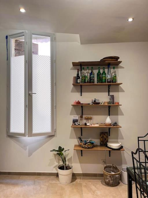 een kamer met planken met flessen en een raam bij Appartement charmant et calme dans l’Hérault in Poussan