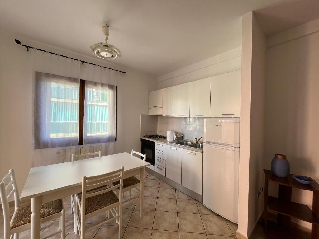 - une cuisine avec des placards blancs, une table et des chaises dans l'établissement Appartamento bilocale 4 posti Olbia Codice IUN R3972, à Olbia