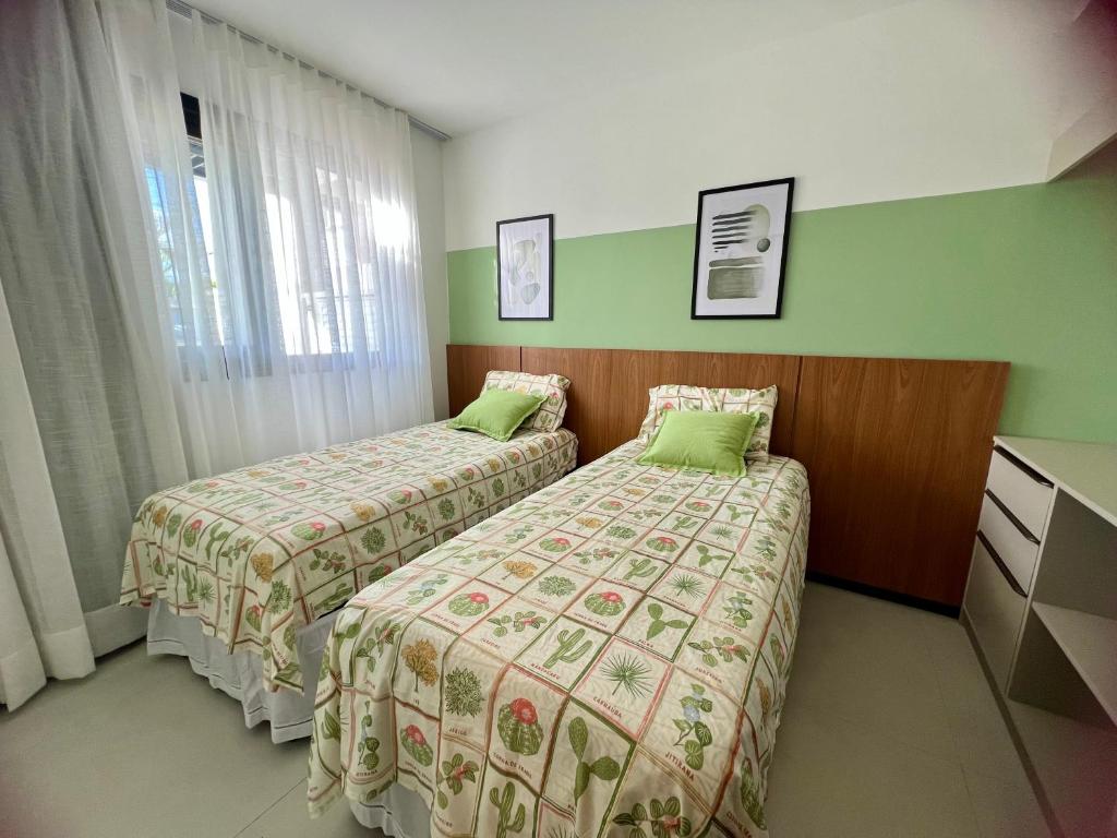 duas camas num quarto de hotel com paredes verdes em Village encanto - 2 quartos, luxo, térreo e lindo na Praia do Forte na Praia do Forte