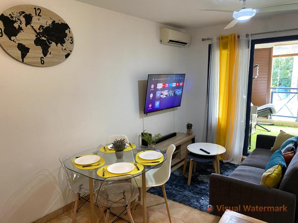 a living room with a table and a tv at Charmant T2 - Moufia Sainte-Clotilde vue Mer & Montagne in Saint-Denis