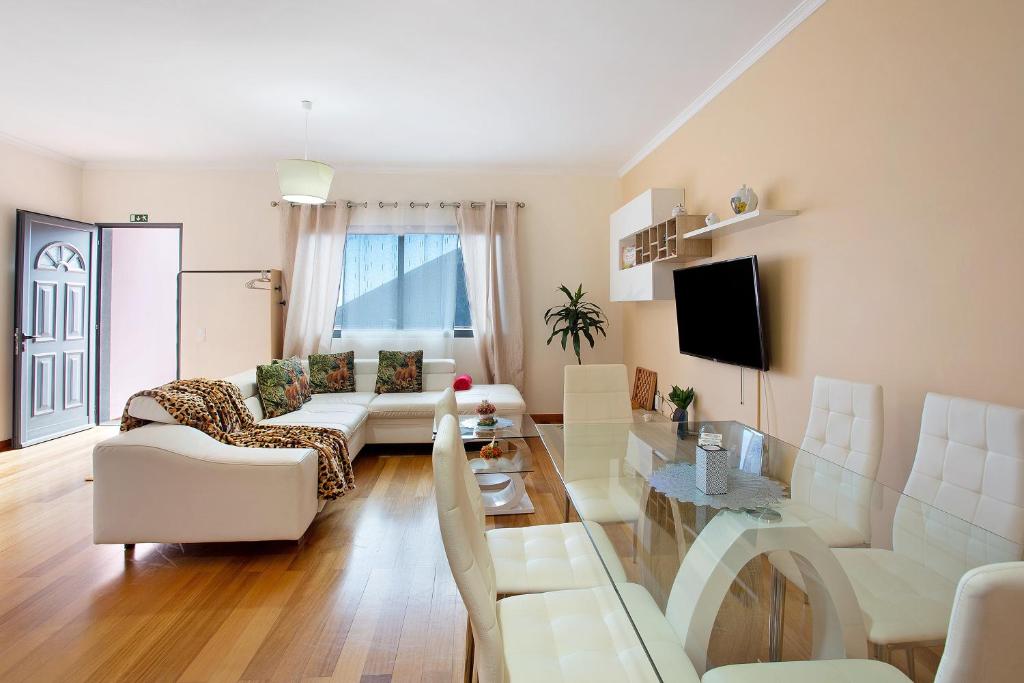 a living room with white furniture and a tv at Moradia Casa Feliz in Santa Cruz
