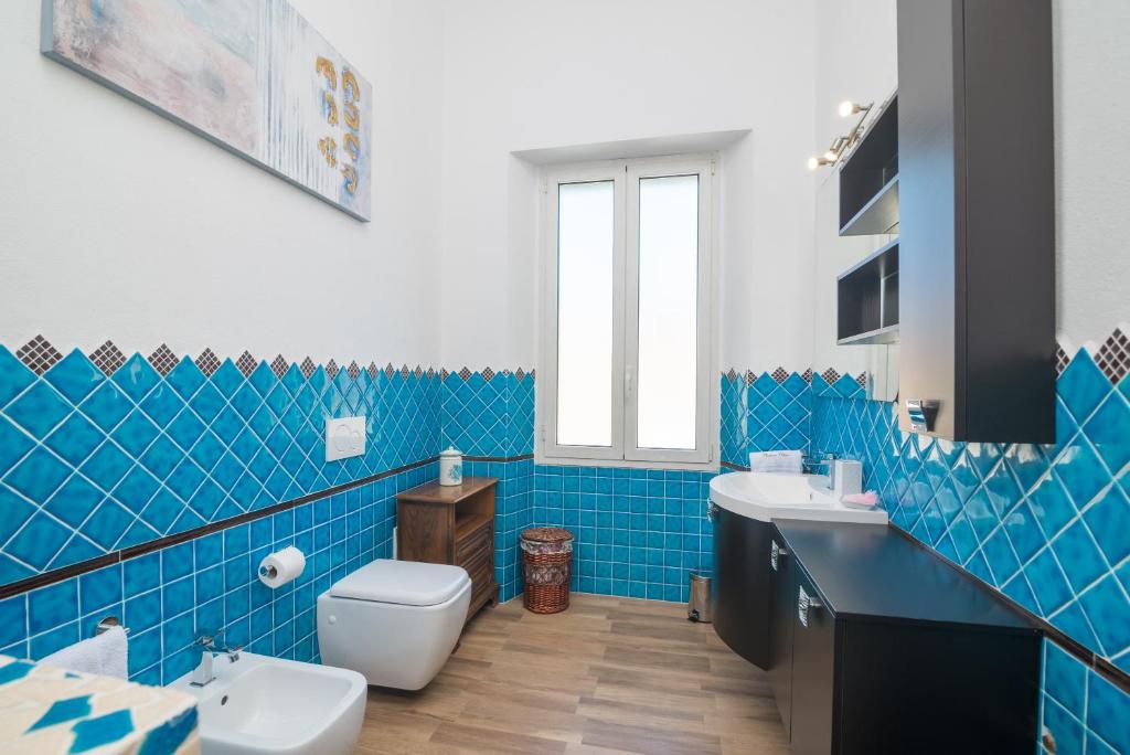 bagno piastrellato blu con servizi igienici e lavandino di Maison Chloe a La Maddalena