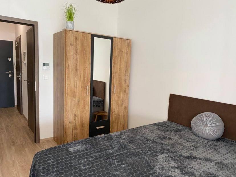 a bedroom with a bed and a wooden cabinet at Bala Beach Siófok Apartman in Siófok